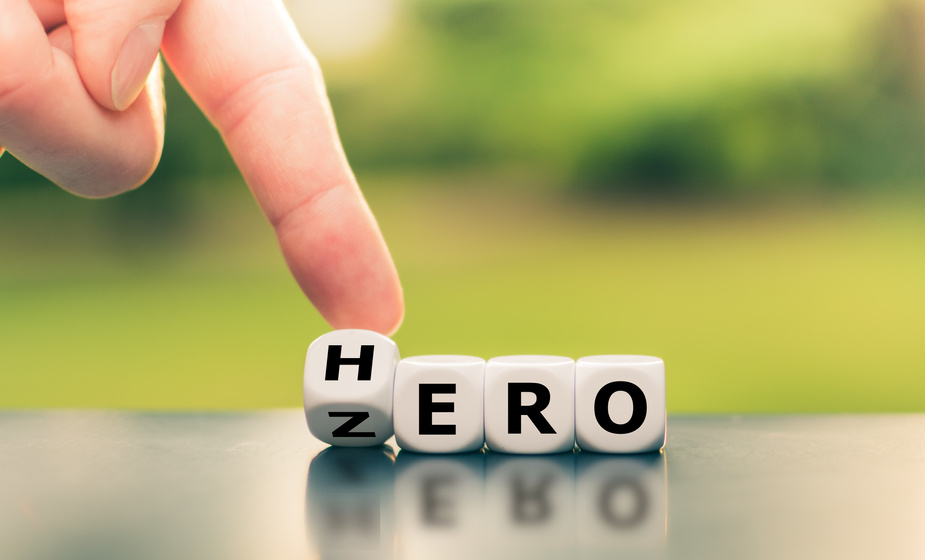 From zero to hero concept. Hand turns a dice and changes the word "zero" to "hero".